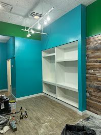 A room with blue walls and white shelves is being remodeled.