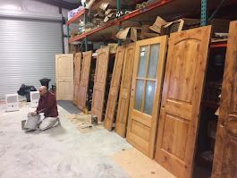 A man is sitting on the floor in a room filled with wooden doors.