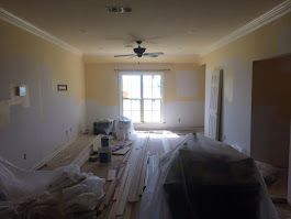 A living room that is being painted with a ceiling fan.