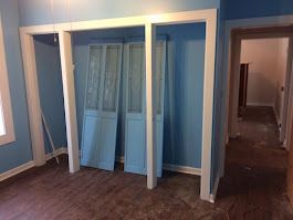 A room with blue walls and a closet with blue doors.