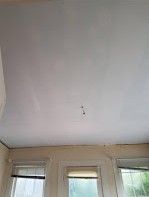 A white ceiling in a room with windows and blinds.