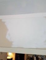 A white wall is being painted in a room.