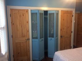 A bedroom with a bed and a closet with blue doors.