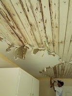 A man is working on a wooden ceiling in a kitchen.