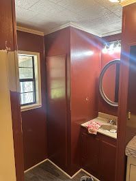 A bathroom with red walls , a sink , a mirror and a window.