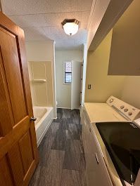A laundry room with a washer and dryer and a bathtub.