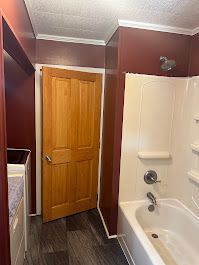 A bathroom with a tub , shower , and wooden door.