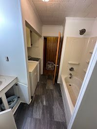A bathroom with a bathtub , sink , washer and dryer.