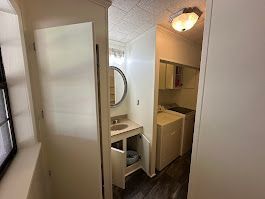 A bathroom with a sink , mirror , washer and dryer.