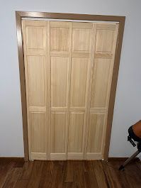 A wooden closet door is open in a room with hardwood floors.