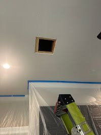 A ladder is sitting under a hole in the ceiling.