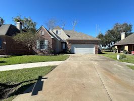 A brick house with a garage and a driveway in front of it.