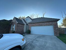 A white truck is parked in front of a brick house with a garage door.