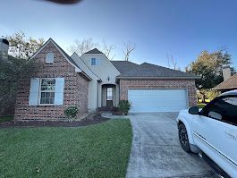 A white truck is parked in front of a brick house.