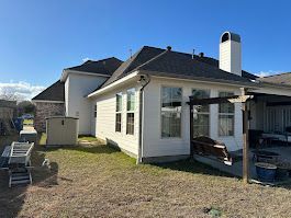 A large white house with a lot of windows and a patio in the backyard.