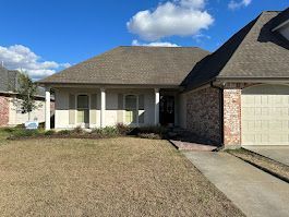 A white house with a brown roof and a white garage door is for sale.