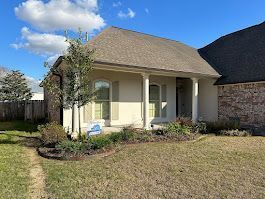A small white house with a large lawn in front of it.