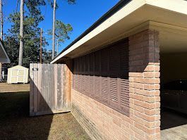 A brick house with a wooden fence in front of it.