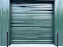 A green garage door is sitting in front of a green building.