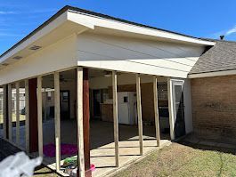 A house with a screened in porch and a refrigerator in the backyard.