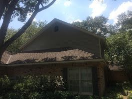 A house with a roof that has been damaged by a tree.