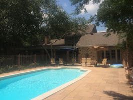 There is a large swimming pool in the backyard of a house.