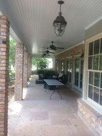 A large porch with a table, chairs and ceiling fans.