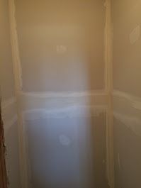 A closet with drywall on the walls and a door.