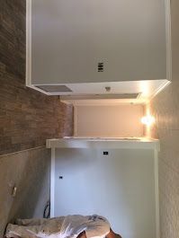 A man is laying on the floor in a room with a ceiling fan.