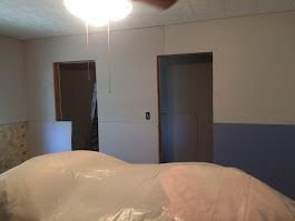 A horse is wrapped in plastic in a room with a ceiling fan.