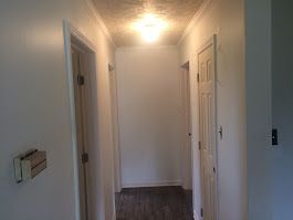 A hallway with white walls and wooden floors in a house.