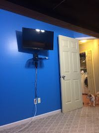 A blue wall with a flat screen tv mounted on it.