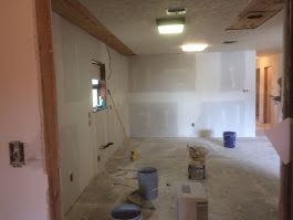 A room that is being remodeled with buckets on the floor.