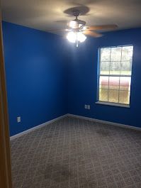 A bedroom with blue walls and a ceiling fan.