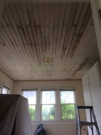 A room with a wooden ceiling and a ladder in it.