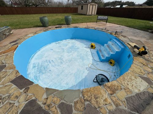 A swimming pool is being built in a backyard surrounded by rocks.