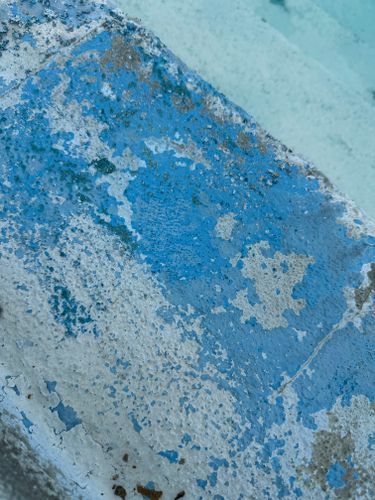 A close up of a blue and white wall with peeling paint