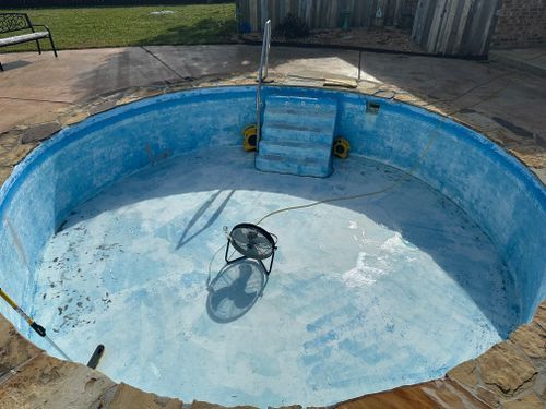 An empty swimming pool with a fan in the middle of it.