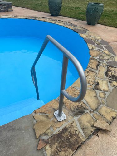 A metal railing leading to a blue swimming pool