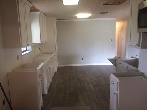 A kitchen with white cabinets and wooden floors is being remodeled.