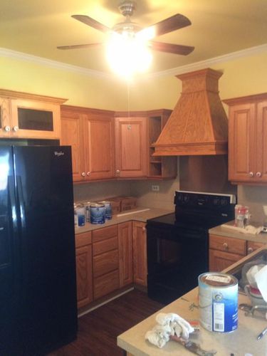 A kitchen with wooden cabinets and a black refrigerator