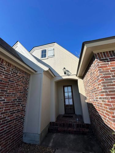 A white house with a brick wall and a door.