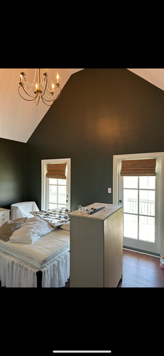 A bedroom with a bed , dresser , window and chandelier.