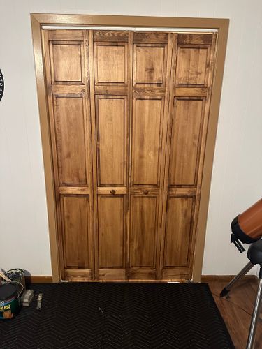 A wooden closet door is sitting in a room next to a telescope.