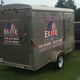 A trailer with the word elite on it is parked next to a truck.