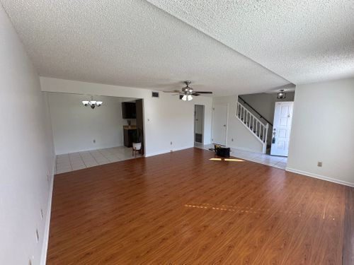 An empty living room with hardwood floors and a ceiling fan.