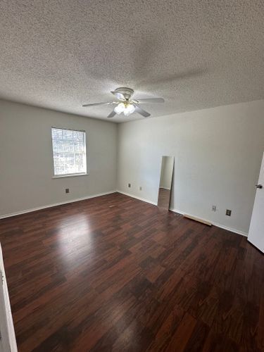 An empty bedroom with hardwood floors and a ceiling fan.