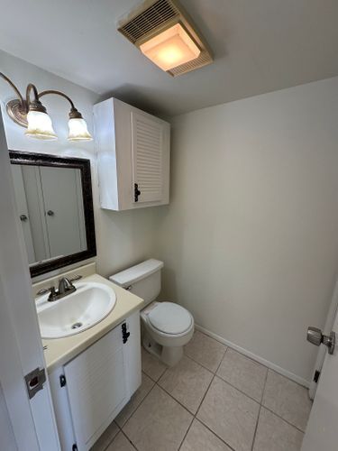 A bathroom with a sink, toilet and mirror.