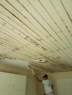 A man is painting the ceiling of a room