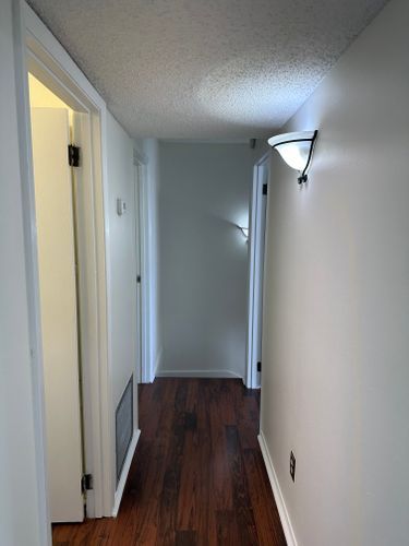 A hallway with hardwood floors and white walls in a house.
